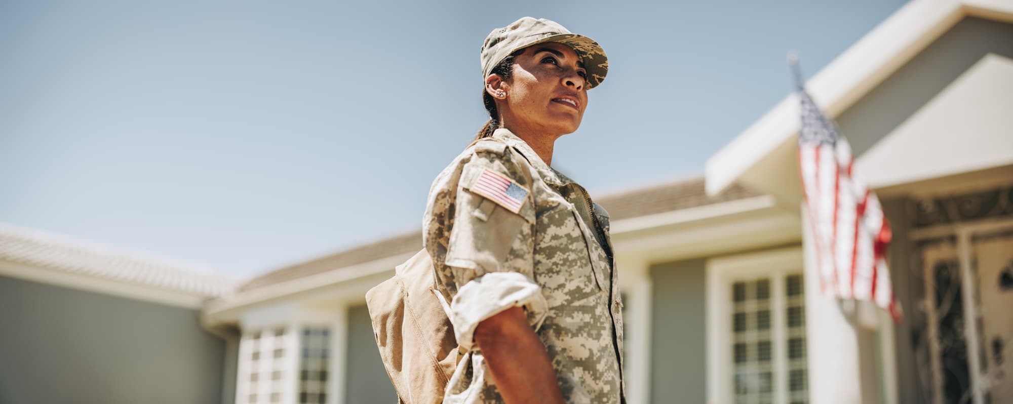 Woman veteran in front of house with American flag