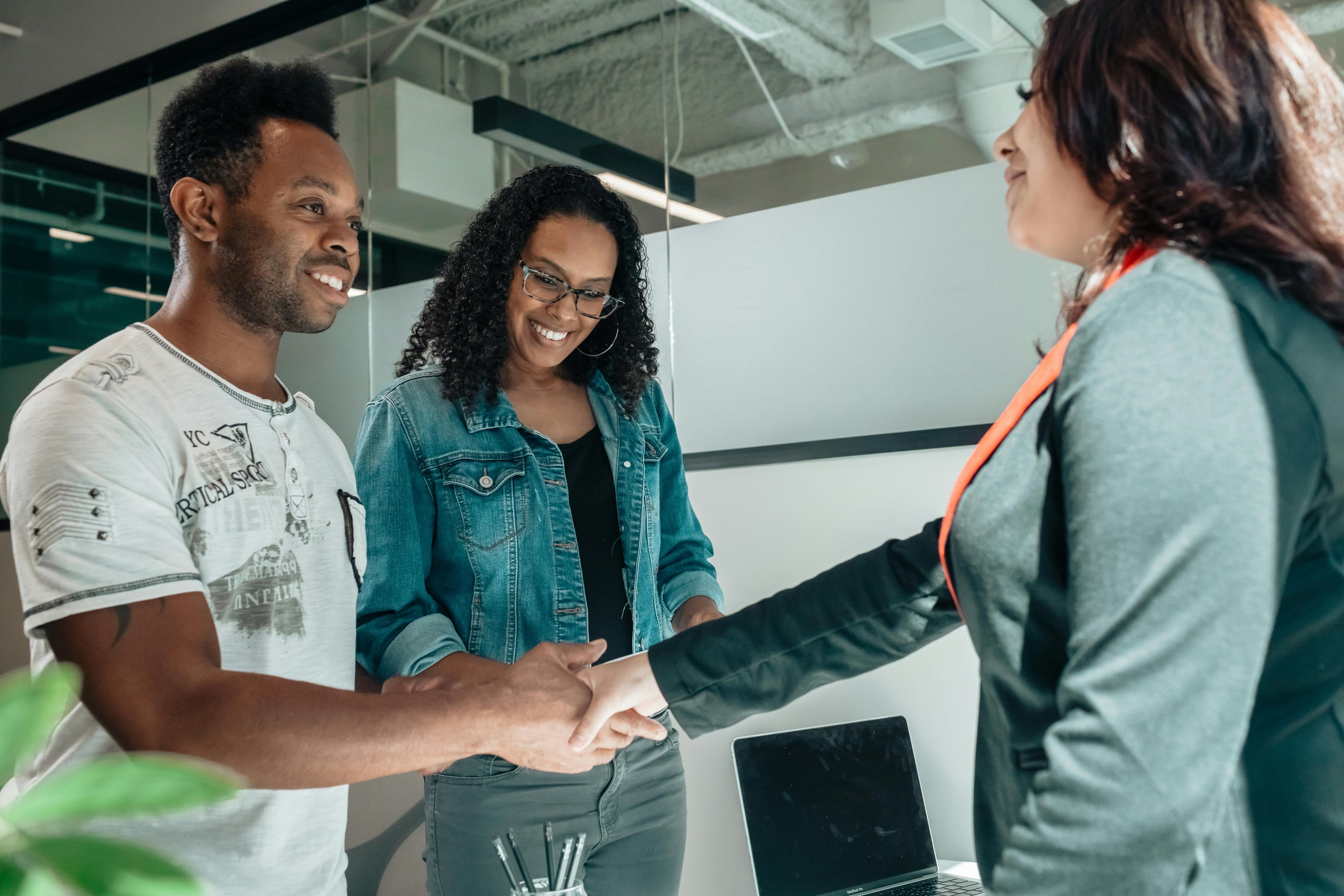 Three people talking to each other with one man and woman shaking hands