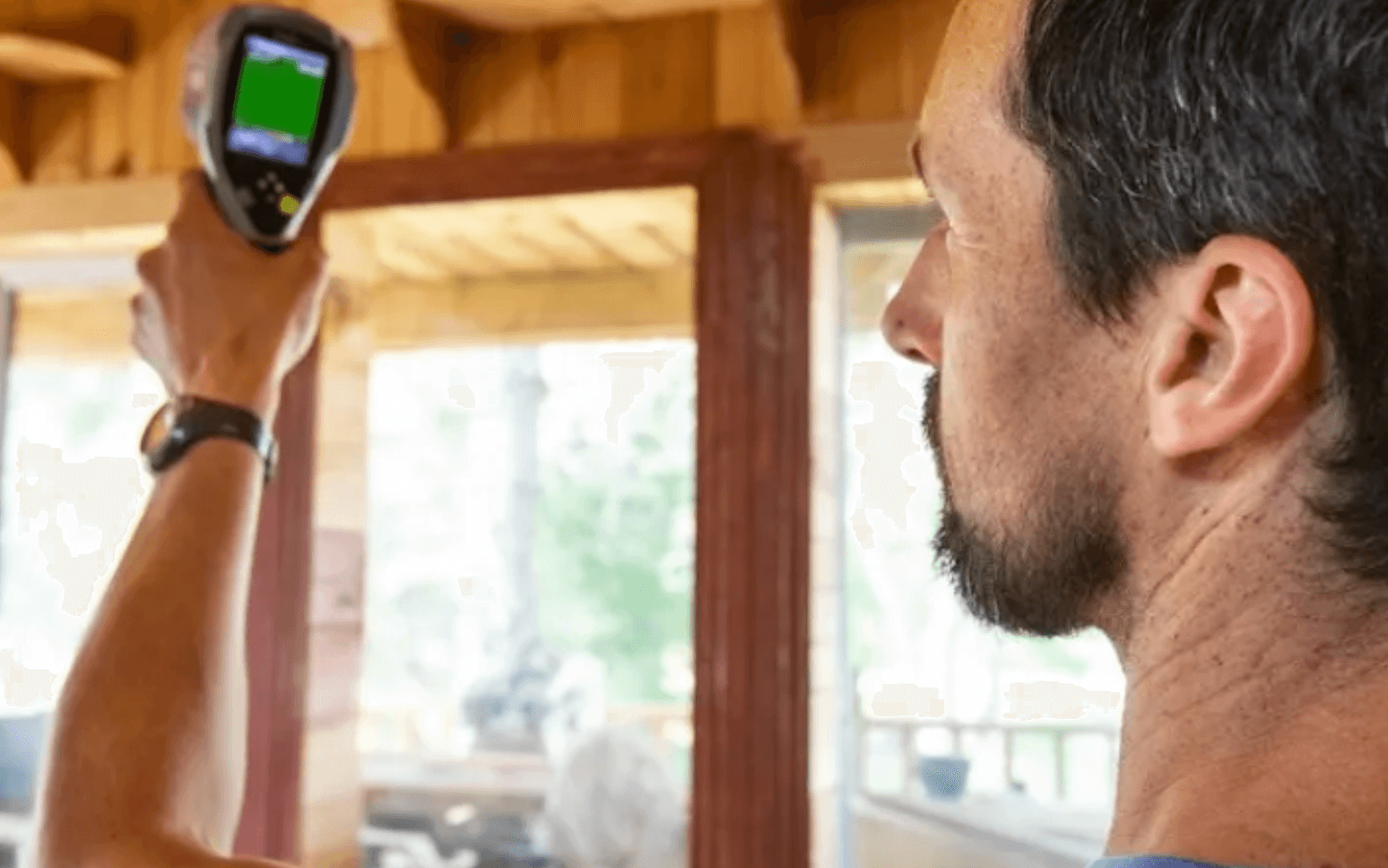 A close-up and side view of a man taking a reading with a infrared gun.